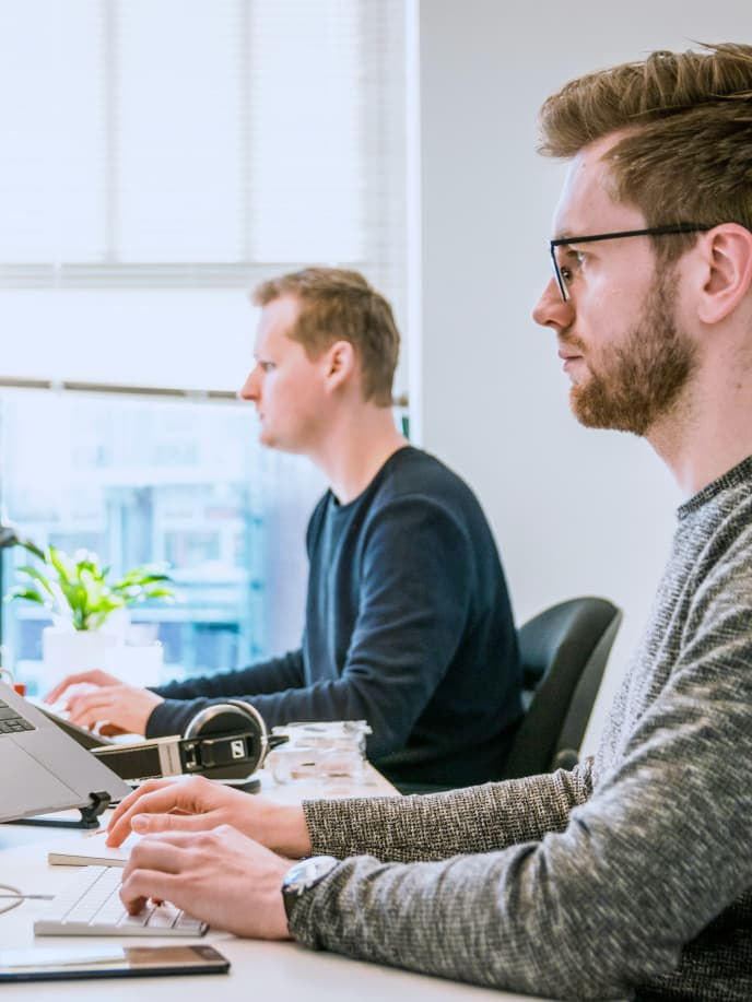 Two developers working side by side at their desks