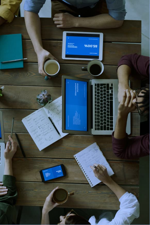 Team in a meeting with tablets, laptops, and notes