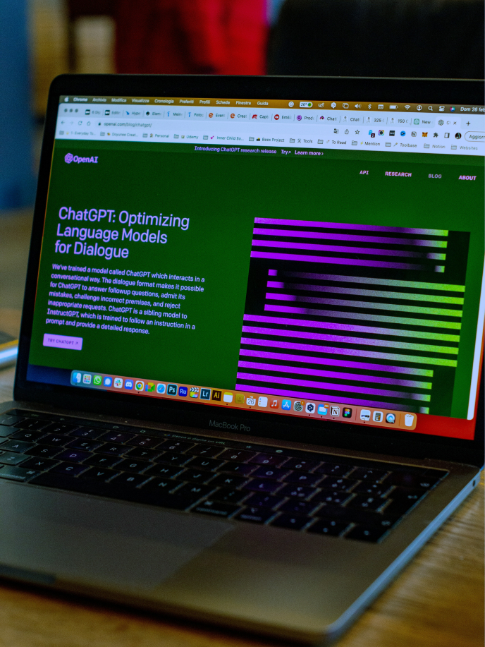 A laptop screen displays a webpage about ChatGPT, a language model for dialogue