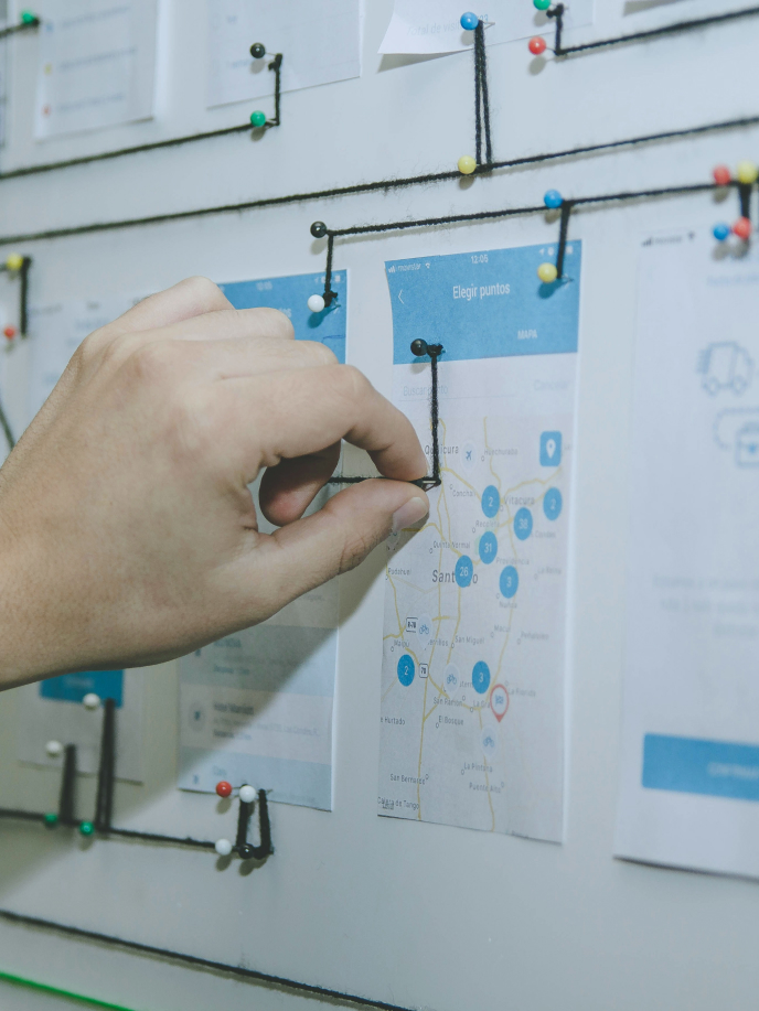 A hand is placing a pin on a map displayed on a white board