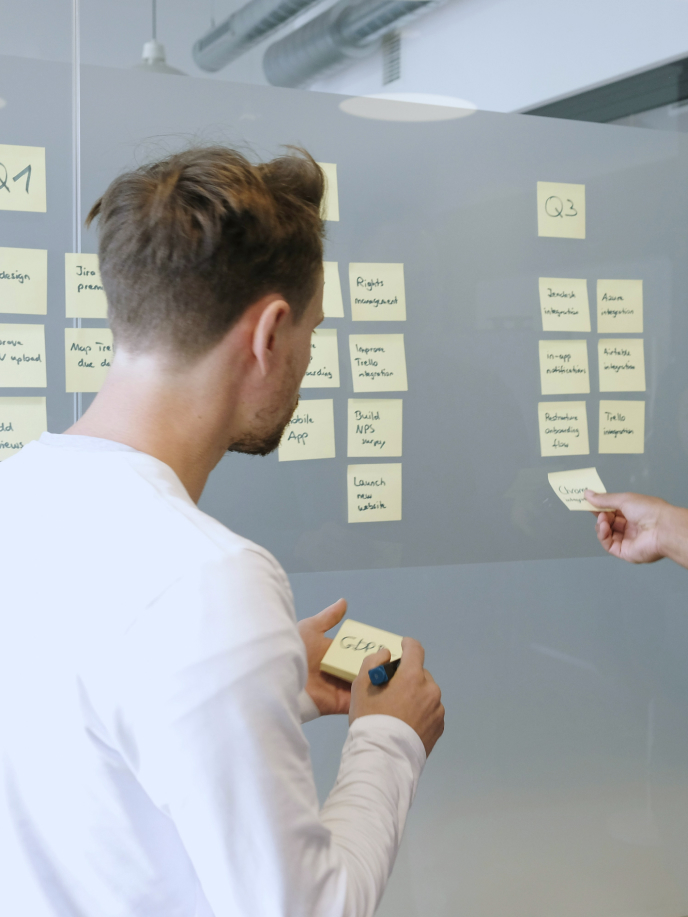 A person is reviewing a whiteboard with lists of tasks and project items